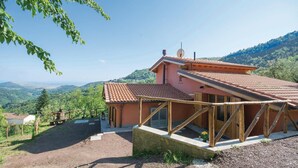 Ein Haus mit geneigtem Dach, einem Steinfundament und Blick auf eine gebirgige Landschaft.