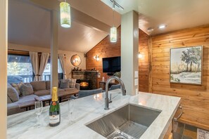 A modern kitchen with a marble countertop, stainless steel sink, and pendant lighting. - Large Sherwin Villas Mammoth Getaway (Mammoth Lakes)