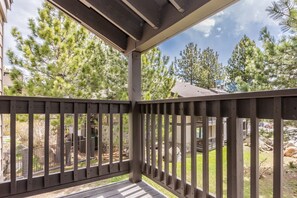 Enjoy the serene view from this deck overlooking a beautifully landscaped backyard with trees, a garden, and a natural rock formation.
