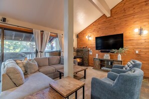 Relax in this stylish living room with a large flat-screen TV, comfortable sofa, and two armchairs.