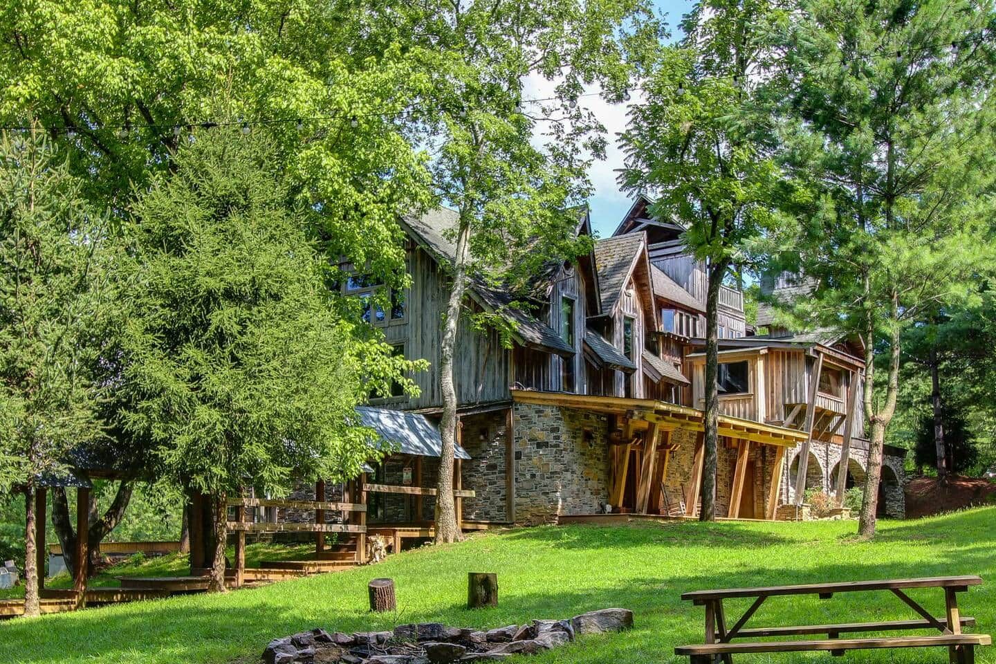 Une cabane rustique, avec des fondations en pierre et une structure supérieure en bois, entourée d’une végétation luxuriante.