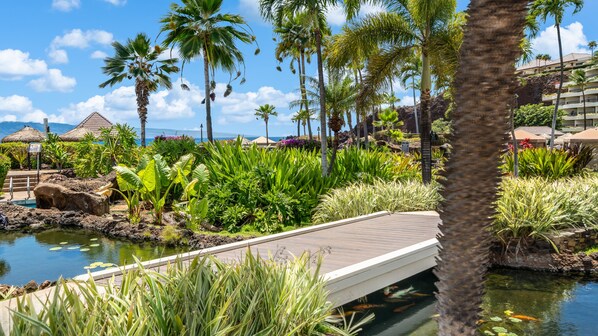 A resort with a pool, palm trees, and a bridge.