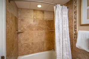 A bathroom with a bathtub, a shower curtain, and a towel rack.