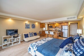 Een moderne hotelkamer met een groot bed, een bank, een televisie, een kitchenette en een eettafel.