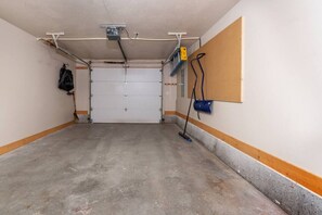 A parking garage with a concrete floor, a closed garage door, and a wall-mounted blue fire extinguisher.