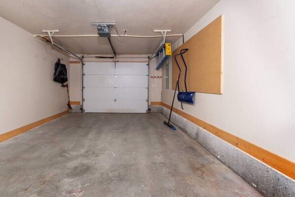 A parking garage with a concrete floor, a closed garage door, and a wall-mounted blue fire extinguisher.