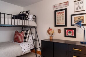 A bunk bed with a globe and framed pictures on the wall.