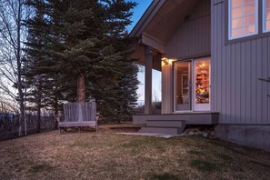 A house with a porch, a bench, and a large tree.