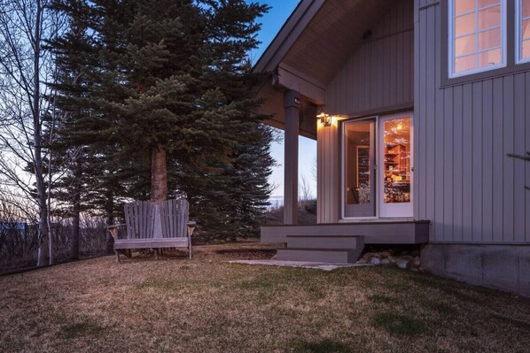A house with a porch, a bench, and a large tree.