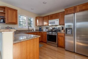 A modern kitchen with wooden cabinets, stainless steel appliances, and a granite countertop.