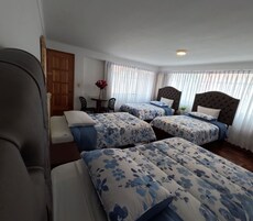 Habitación de hotel con dos camas, una mesita con un florero y una silla.