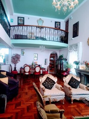 A spacious living room with a herringbone wood floor, a balcony with a wrought iron railing, and a chandelier. - Residencial Belle Maison (Cusco)