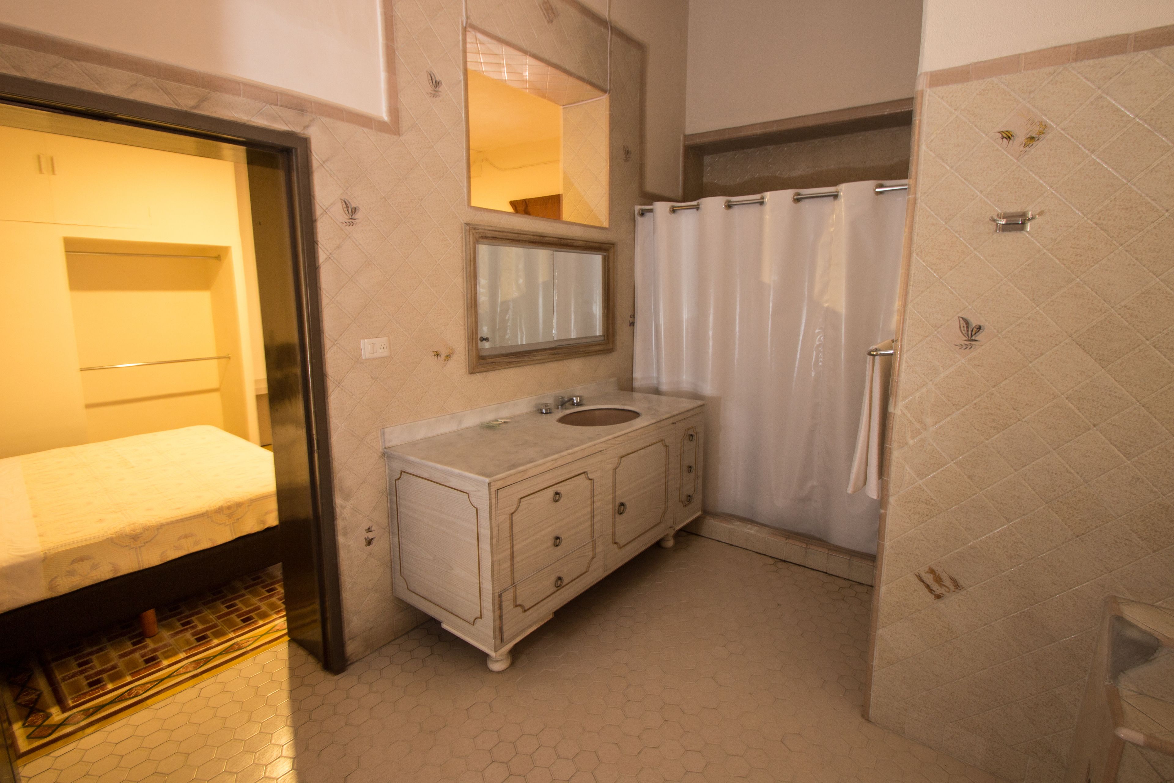 Een badkamer met een wastafel, spiegel en douchegordijn.