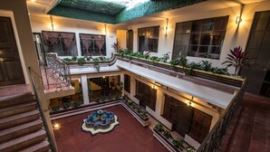 Ein mehrgeschossiges Atrium mit einer zentralen Fontäne, mehreren Balkonen und üppiger Bepflanzung.