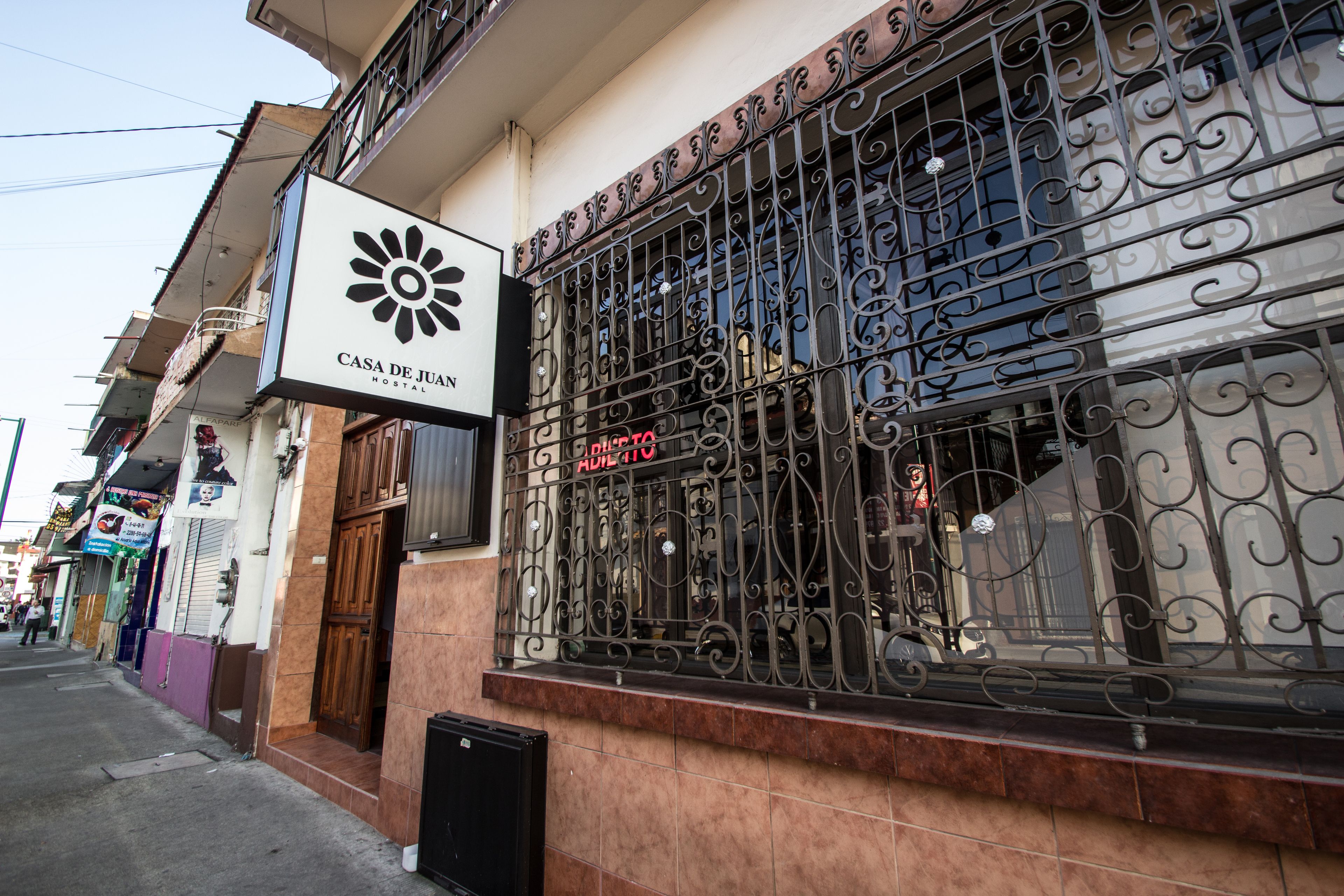 A building with a sign reading "CASA DE JUAN HOSTAL" and a wrought iron gate with "ADULTO" written on it.