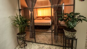 Ein Schlafzimmer mit einem Bett, Vorhängen und zwei Zimmerpflanzen.