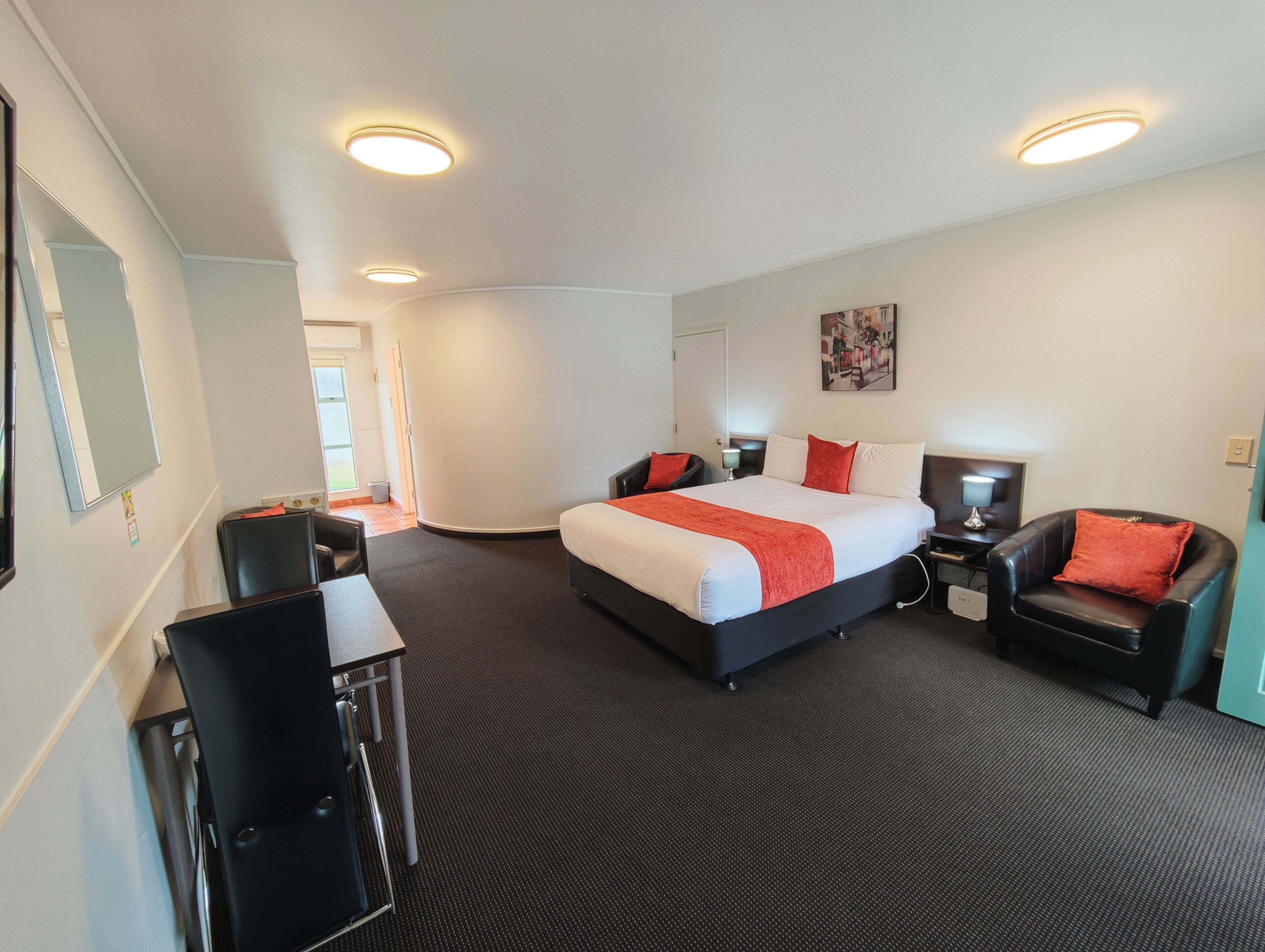 A hotel room with a large bed, two bedside tables, a desk, a chair, and a mirror.
