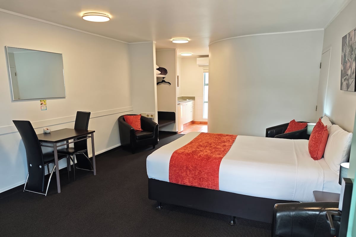 Une chambre d’hôtel avec un lit, un bureau, une chaise et une petite table.