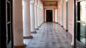 A corridor with white columns and a checkered floor, leading to a doorway. - Casa del Árbol Hostel (Concepción del Uruguay)