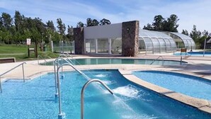 A swimming pool with a glass-enclosed structure in the background. - Casa del Árbol Hostel (Concepción del Uruguay)