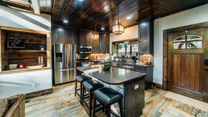 Una cocina moderna con una isla grande, electrodomésticos de acero inoxidable y un techo de madera rústica.