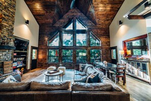 Un salón amplio con techo alto, ventanas grandes, chimenea y una zona de estar acogedora.