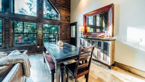 Un interior rústico de madera con una mesa de comedor, sillas y un espejo grande.