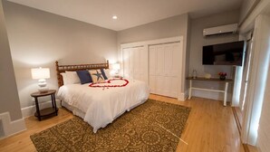 Une chambre à coucher comprenant un lit, une table de chevet, une lampe, un tapis à motifs, une armoire et un appareil de climatisation.