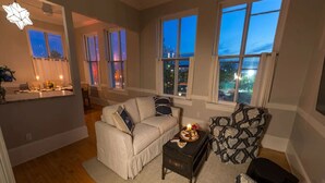 Un salon avec un canapé, une petite table sur laquelle est posée une bougie et un fauteuil à motifs.