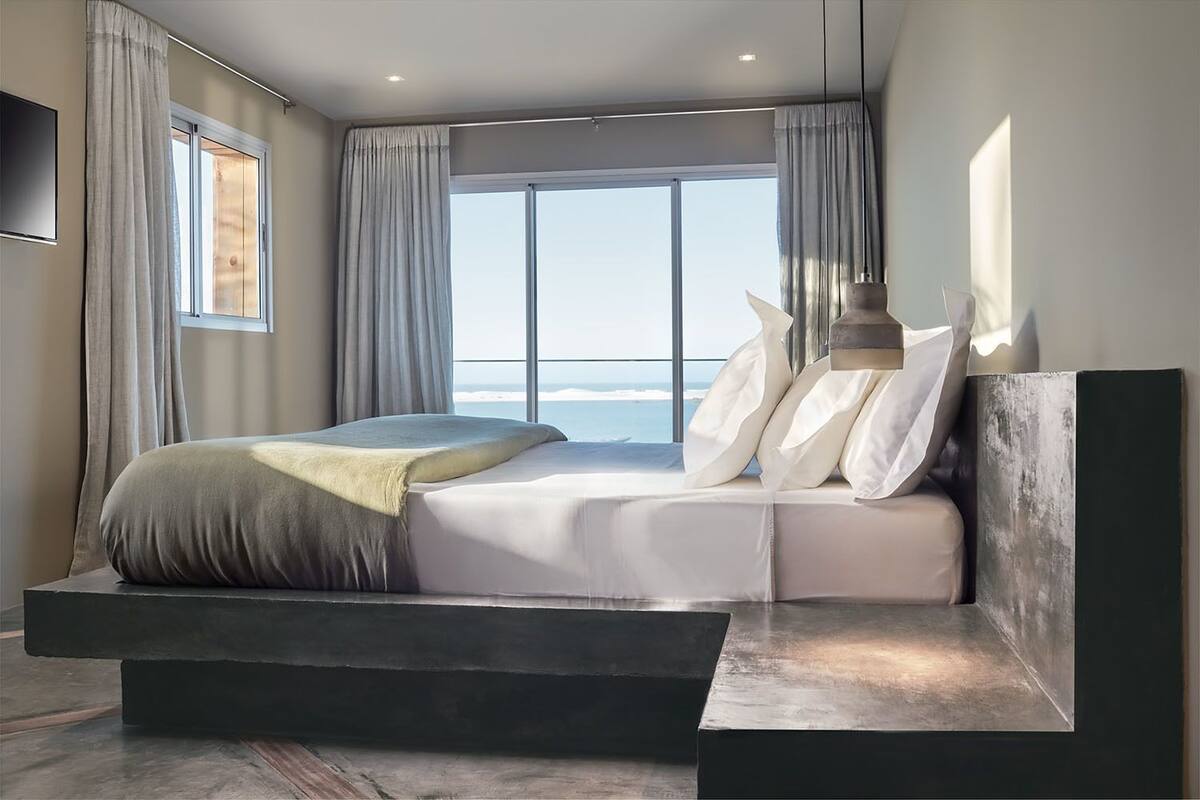 Un dormitorio moderno con una cama grande, vistas al mar y un diseño minimalista.