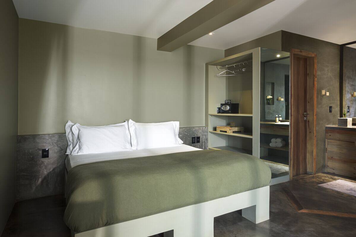 Un dormitorio moderno con una cama grande, un vestidor y un baño con tocador de madera.