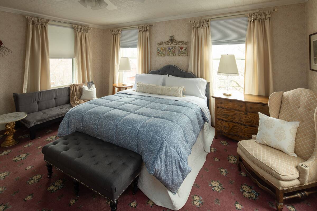 Une chambre à coucher avec un grand lit, un canapé, un fauteuil et une petite table.