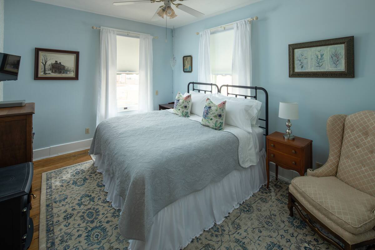Une chambre à coucher comprenant un lit, une table de chevet, une chaise et une commode.
