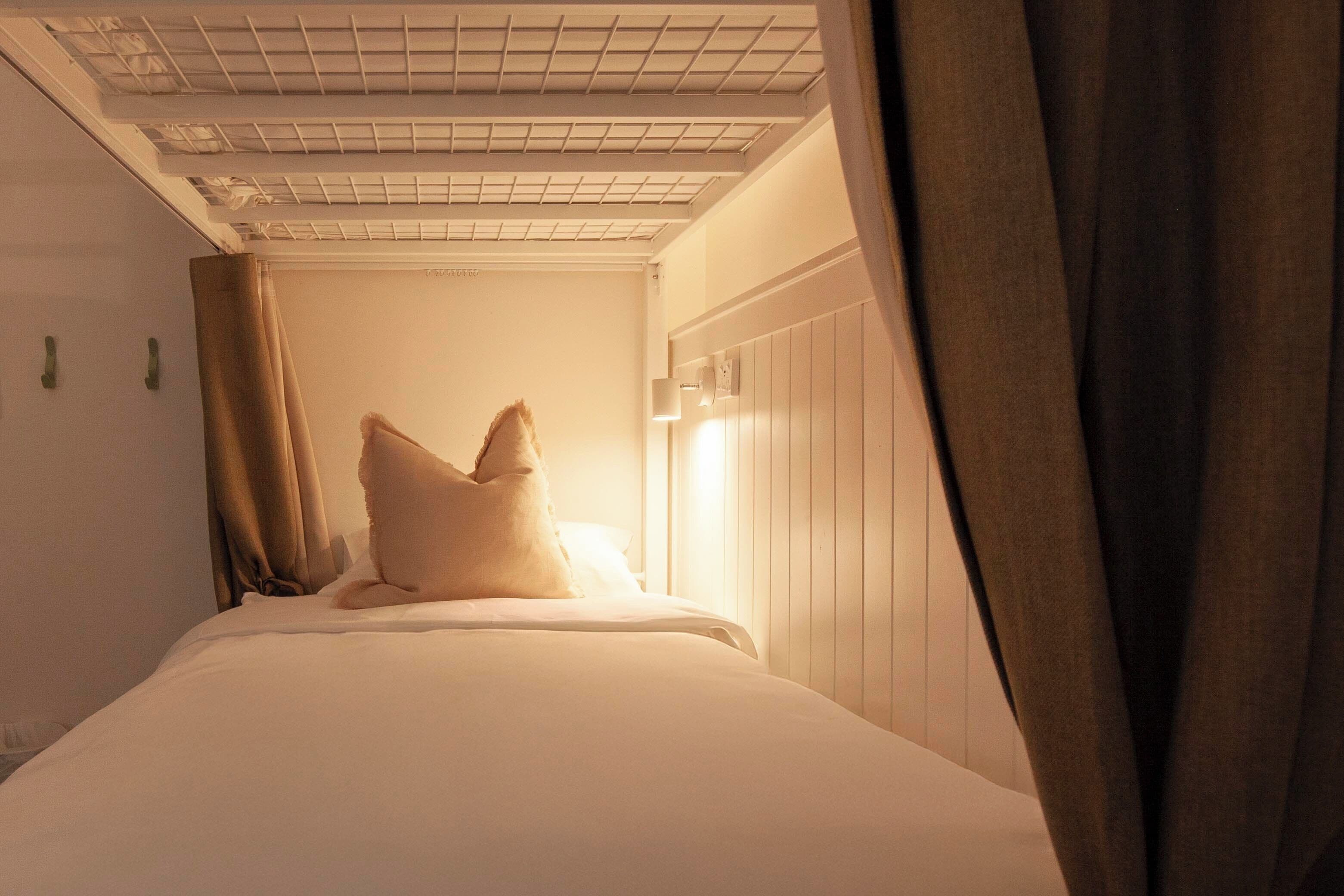 A hotel room with a bed, curtains, and a ceiling with a grid pattern.