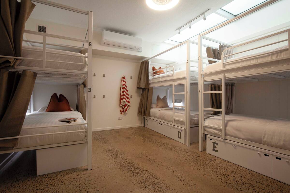 A room with bunk beds, a ceiling fan, and an air conditioning unit.
