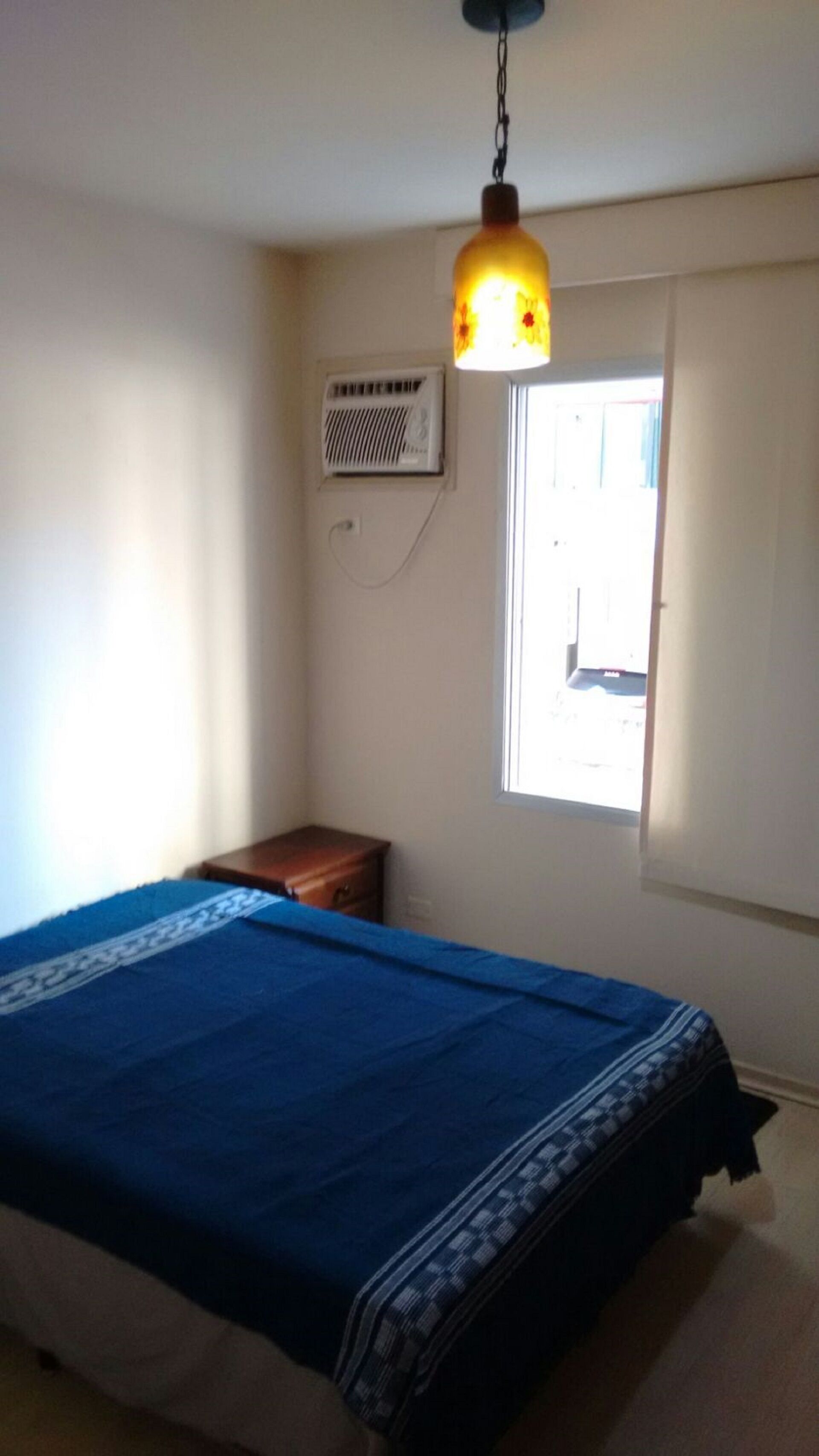 A bedroom with a bed, a window, and an air conditioning unit.