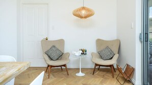 Une pièce moderne avec deux fauteuils, une petite table ronde et un luminaire suspendu.