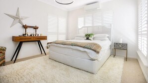 Une chambre à coucher avec un grand lit, une décoration sur le thème des étoiles, une table de chevet en bois et une petite table d’appoint.