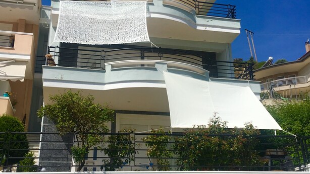 Un edificio de varios pisos con balcones, una pared de piedra y una palmera.