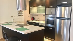 Una cocina moderna con una isla central, electrodomésticos de acero inoxidable y muebles oscuros.
