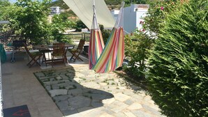 Un patio con una mesa y sillas, una hamaca y vistas a una colina con edificios al fondo.