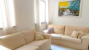 En stue med to beige sofaer, en farverig pude og et maleri på væggen.