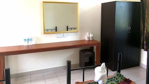 Une pièce avec un bureau en bois, une armoire noire, un miroir et un petit tapis.