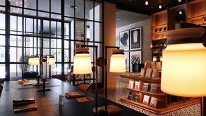A modern interior with a long table, books, and shelves with books and decorative items. - The Mumian Hotel Shenzhen Houhai (Shenzhen)