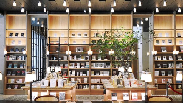 A library with multiple tables and chairs, bookshelves, and a large window. - The Mumian Hotel Shenzhen Houhai (Shenzhen)