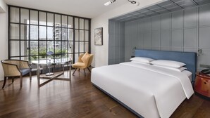 A modern hotel room with a large bed, a seating area with a table and chairs, and a view of the city through large windows. - The Mumian Hotel Shenzhen Houhai (Shenzhen)