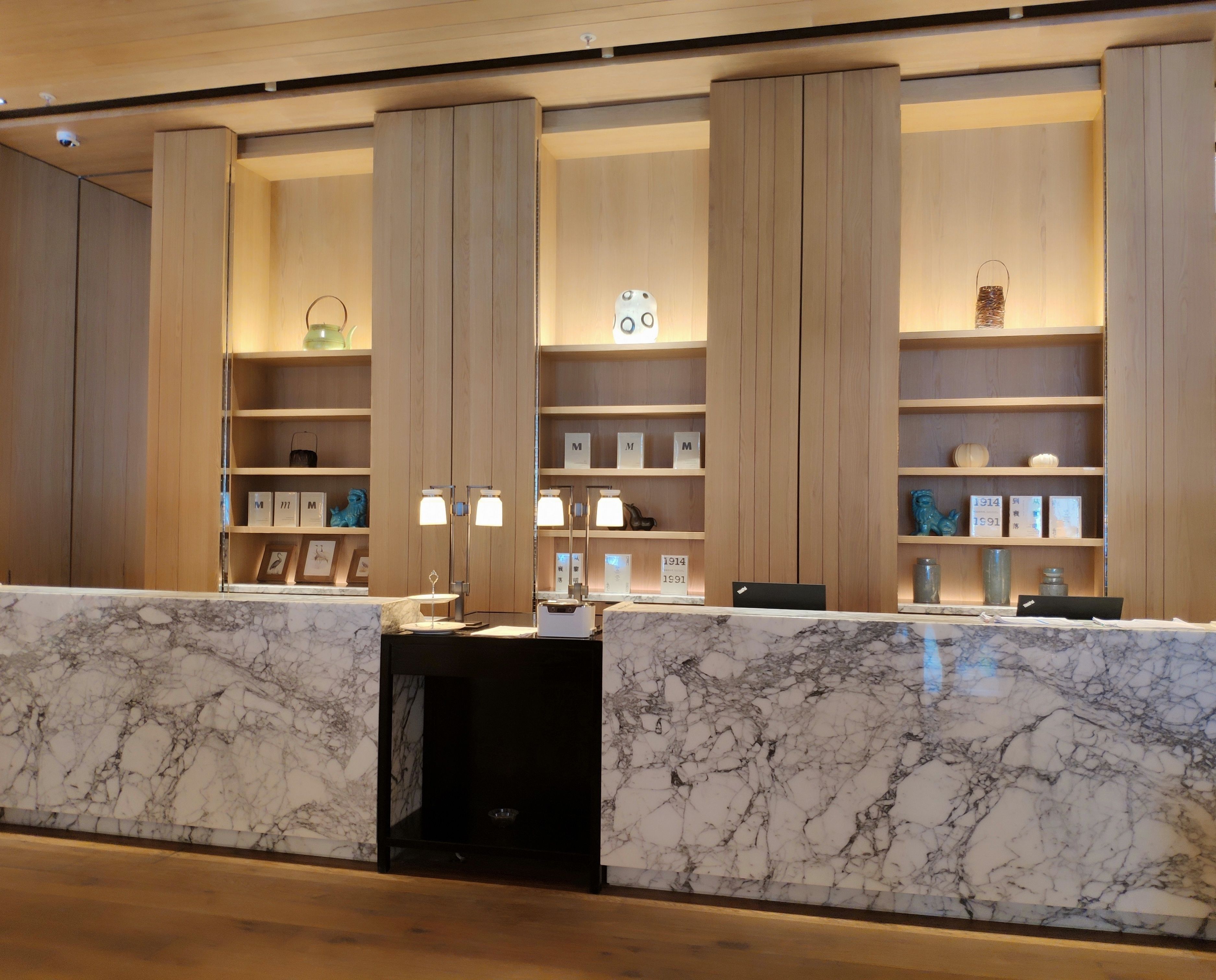 Un área de recepción con mostradores de mármol, estanterías de madera y objetos enmarcados.