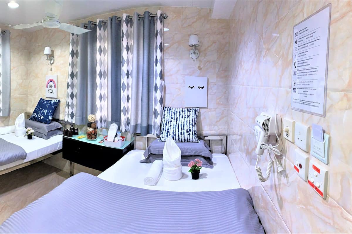 A hotel room with a bed, bedside table, and a bathroom with a shower and toilet.