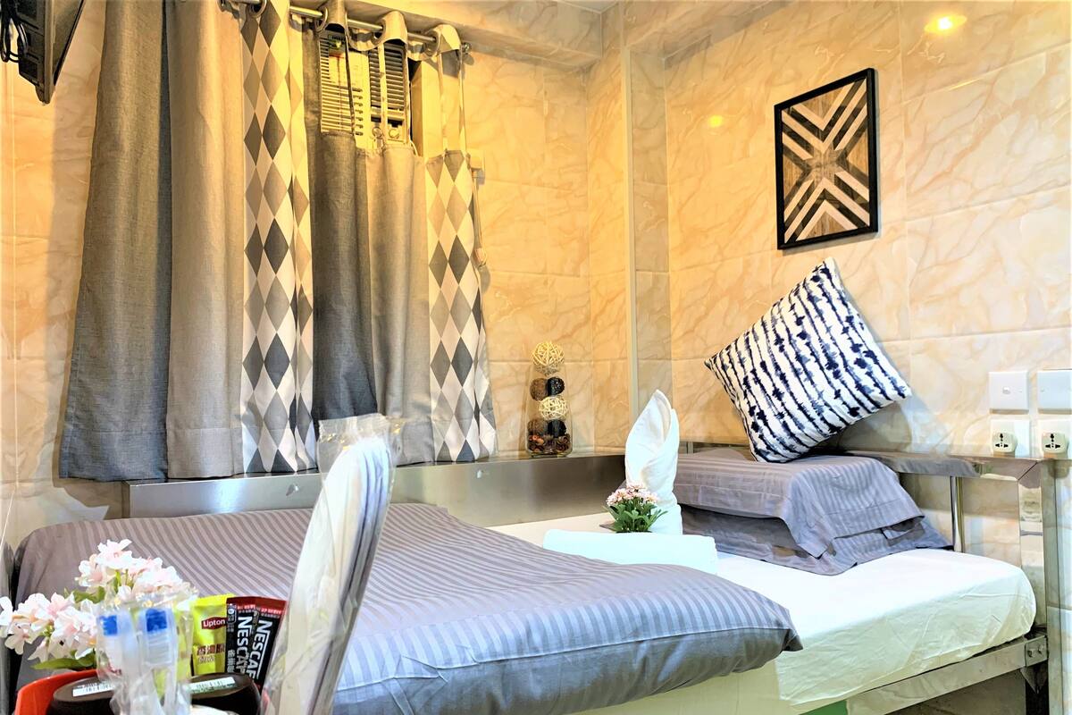 A hotel room with two beds, a shower area, and a wall-mounted light fixture.