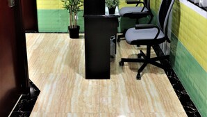 A reception area with a marble floor, a reception desk, two office chairs, a potted plant, and a wall with a floral pattern. - Super Guest House (Kowloon)